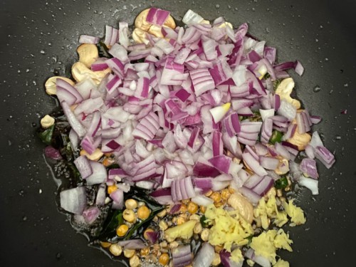 Grated ginger, onions and chilies added to a black non-stick wok