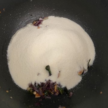 Sooji / semolina widow to the softened onions in a black, non-stick wok