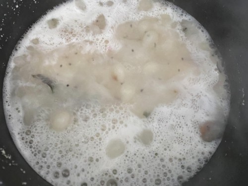 Hot water to rava / suji mixture in a black non-stick wok