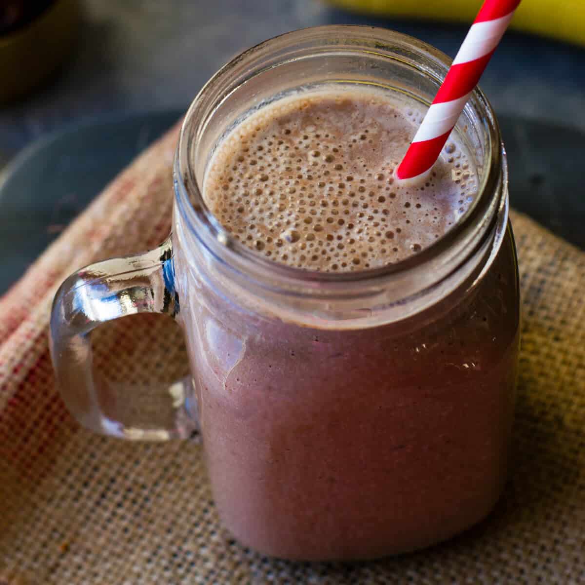 chocolate almond smoothie in a mason jar with straw on a burlap napkin