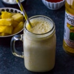 Pineapple orange smoothie served in a ball jar with a straw