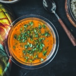 Udupi rasam served in a glass bowl with a spoon on the side