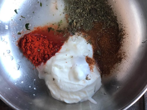 yogurt, chili powder, garam masala and other spices in a steel bowl